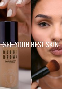 Bobbi Brown Weightless Skin Foundation i en frostet glassflaske med svart hette, sammen med en sminkebørste mot en nøytral bakgrunn.