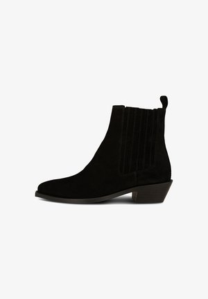 Stivali alla caviglia in suede nero con punta affusolata, pannelli laterali elasticizzati e tacco basso impilato. La texture è morbida con dettagli di cucitura verticale.