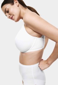 Sujeción blanca sin costuras con una sola tira en el hombro, diseñada para la comodidad. Tejido liso con un panel ligeramente texturizado en la parte posterior. Ropa interior a juego de cintura alta.