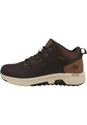 Chaussure mi-haute en cuir marron avec des accents beige, des œillets en métal et une tige synthétique texturée marron foncé. Semelle rembourrée beige et noire.
