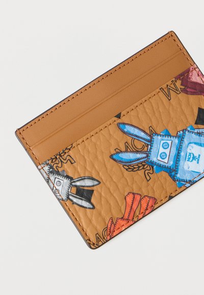 Καφέ δερμάτινη θήκη κάρτας με διασκεδαστικές απεικονίσεις κουνελιών σε μπλε, κόκκινο και μαύρο. Διαθέτει πολλαπλές θήκες για κάρτες και υφή στην επιφάνεια.