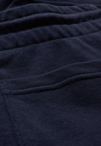 Gros plan sur un tissu bleu marine montrant des coutures cousues et un matériau tricoté doux et texturé.