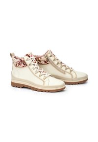 Botas de tobillo de cuero beige con un forro texturizado de patrón rosa y marrón, herrajes en tono dorado y una suela marrón resistente.
