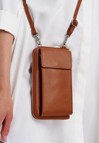 Braune Umhängetasche aus Leder mit strukturierter Oberfläche, ausgestattet mit einem Vorderklappendeckel, einem Reißverschluss und einem verstellbaren Trageriemen.