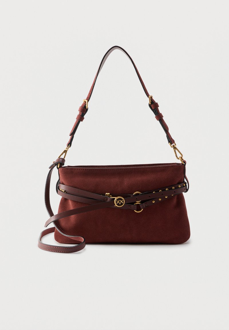 Καφέ τσάντα ώμου από σουέντ με ρυθμιζόμενο ιμάντα και διακοσμητική ζώνη με καρφιά, που διαθέτει μικρό στρογγυλό χρυσό έμβλημα στο μπροστινό μέρος.