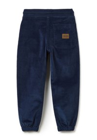 Marinefarbene Cordhosen mit elastischem Bund, schmal zulaufenden Knöcheln und einer Gesäßtasche mit einem beigen Etikett. Weiche Textur und gerippte Details.
