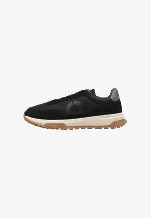 Chaussures de sport noires avec une tige texturée, arborant un logo noir, une semelle intermédiaire crème et une semelle extérieure en caoutchouc brun pour une meilleure adhérence.