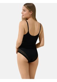 Zwarte bodysuit met verstelbare bandjes, voorzien van doorzichtige geometrische patroon zijpanelen en een gladde textuur, wat zorgt voor een aangesloten silhouet.