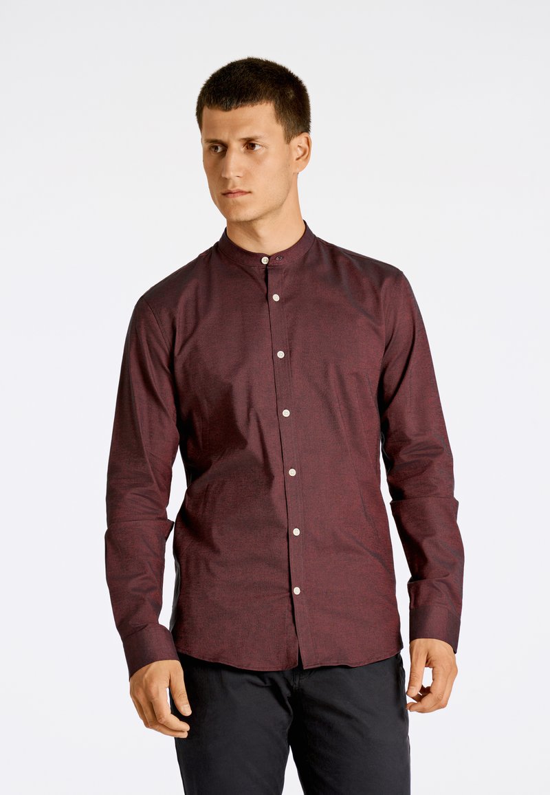 Bordeaux knoopshirt met een bandkraag, lange mouwen en een subtiel textuurpatroon. Voorzien van metalen knopen aan de voorkant.