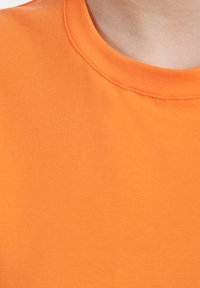 Oranje katoenen T-shirt met een ronde halslijn en een gladde textuur, met een nette afwerking langs de kraag en de stofnaden.
