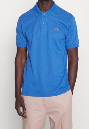 Polo blu realizzato in un tessuto morbido e testurizzato. Presenta una chiusura a tre bottoni e un piccolo logo ricamato sul petto. Maniche corte.