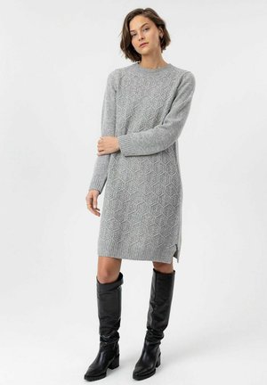 Gray knitted sweater dress featuring a textured hexagonal pattern, long sleeves, and side slits, paired with knee-high black leather boots.