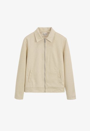 Veste beige avec fermeture éclair, col pointu et deux poches latérales. Fabriquée dans un tissu doux et texturé. Design simple et sans embellissement.