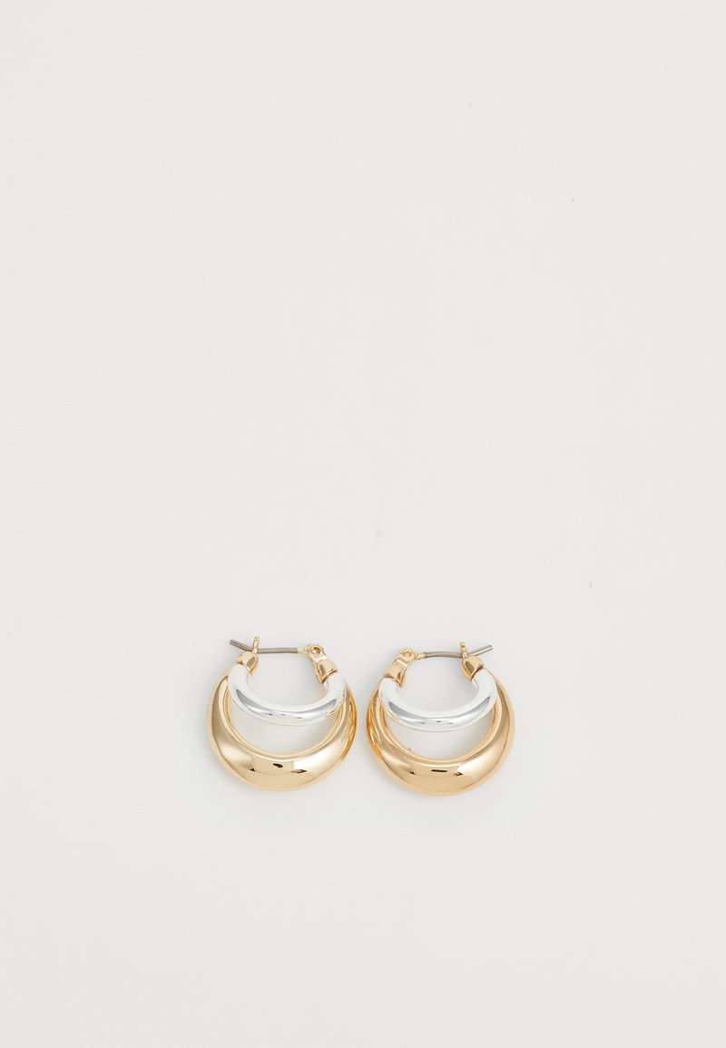 Orecchini a cerchio in oro e argento con un design bicolore, finitura lucida e forma arrotondata. Presentano una chiusura a cerniera per un indossamento sicuro.