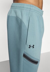 Under Armour UNSTOPPABLE FLEECE - Tracksuit bottoms - jasper blue/serpentine/black