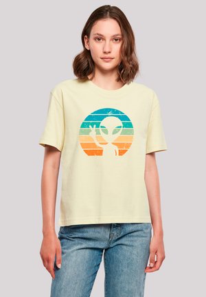Light yellow cotton t-shirt with a distressed graphic of an alien and peace sign within a circular multicolored stripe design.