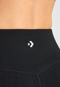 Leggings negros de cintura alta con una textura suave y un logotipo blanco con un diseño de estrella y chevron en la cinturilla.