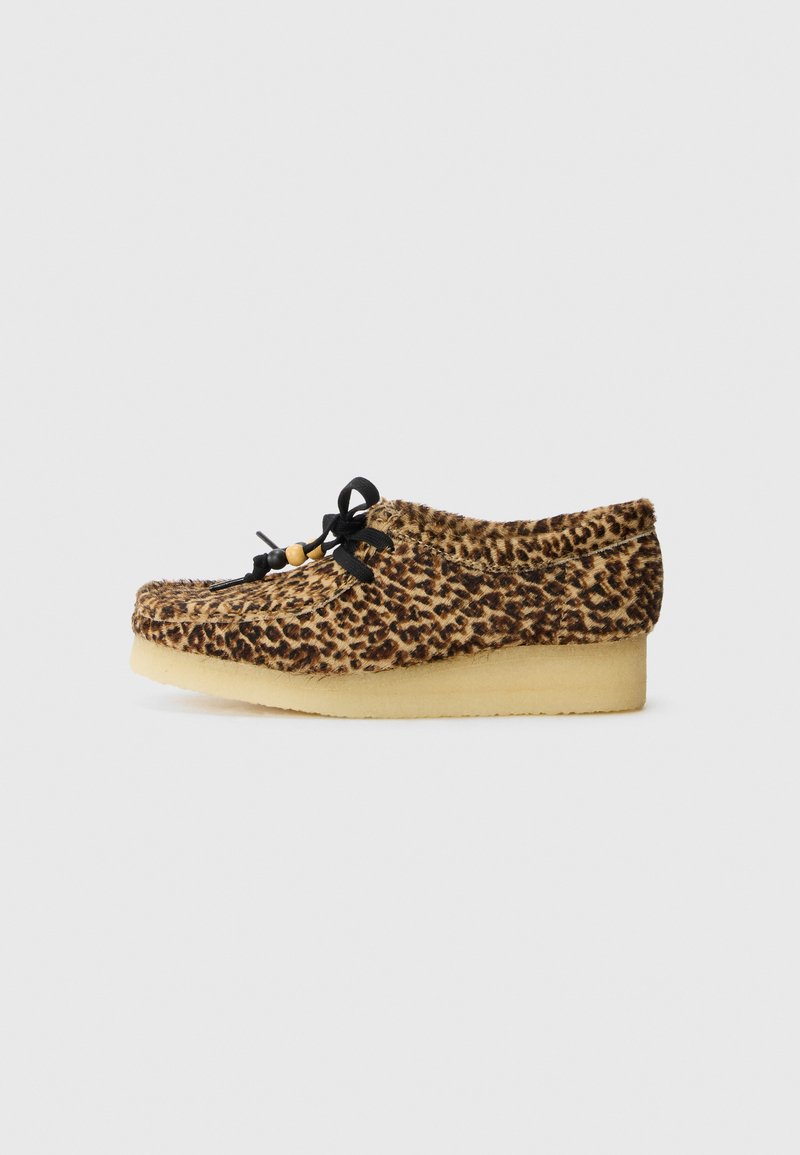 Søte snøresko i leopardmønstret semsket skinn med en myk tekstur, rund tå og en beige gummisåle. Svarte lisser med en tresmykke som aksent.