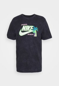 Black short-sleeve Nike t-shirt with neon green logo, palm tree graphic, and pink wave patterns on the chest.