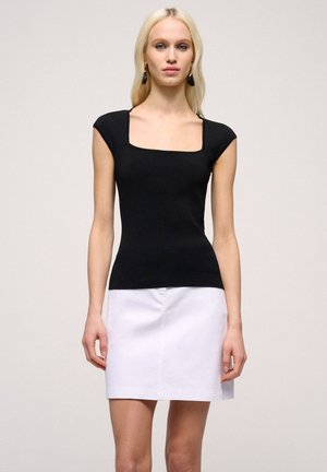 Top scurt cu maneci scurte, cu dungi negre, având decolteu pătrat, asortat cu o fustă mini albă, cu o textură netedă și un design ajustat.