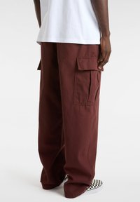 Cargo broek in donker bordeaux katoen, met zijzakken, een ruime pasvorm en een rechte snit; gecombineerd met zwart-witte geblokte schoenen.