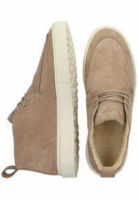 Zapatos de tobillo de ante de color marrón claro con una superficie texturizada, que cuentan con una suela de goma blanca y un tirador en bucle en el talón.