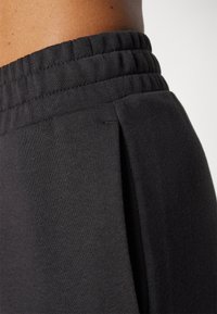 Zwarte sportbroek met een elastische tailleband, voorzien van een geprofileerde stof en zijknopen voor bewegingsgemak.
