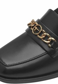 Mocassin en cuir noir avec un accent de chaîne dorée. Texture lisse avec un bout carré et des coutures le long du bord.