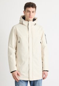 Beige parka-jakke med hætte, frontlynlås og to sidelommer. Fremstillet af et glat stof med et let struktureret design.