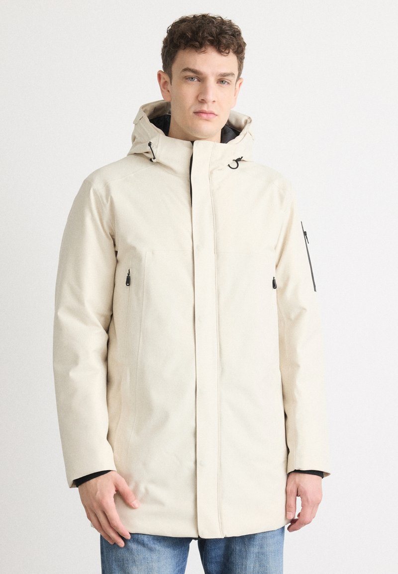 Beige parka-jakke med hætte, frontlynlås og to sidelommer. Fremstillet af et glat stof med et let struktureret design.