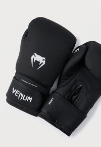 Mănuși de box negre realizate cu un exterior sintetic neted, cu elemente de branding albe și un logo distinctiv, având bretele reglabile pentru încheietură.