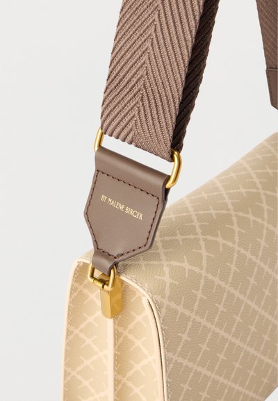 Μπεζ τσάντα με σχέδιο, με φαρδιά καφέ πλεκτή λαβή και χρυσά μεταλλικά στοιχεία, με κείμενο "BY MALENE BIRGER" σε δερμάτινη ετικέτα.
