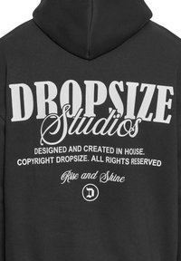 Black hoodie featuring prominent white text design including "DROPSIZE Studios" and other details, with a soft texture and standard hoodie shape.