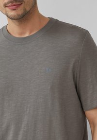 Grijze katoenen T-shirt met een ronde hals, korte mouwen en een subtiele logodetail. De stof heeft een gladde, textuurrijke uitstraling.