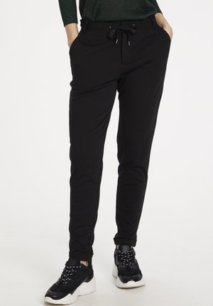 Czarne spodnie dresowe wykonane z miękkiej tkaniny, wyposażone w elastyczny pas ze sznurkiem, boczne kieszenie oraz zwężane mankiety. Akcesoria nie są dołączone.