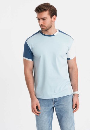 Hellblaues T-Shirt mit kurzen Ärmeln und blauen Akzenten an den Schultern, Rundhalsausschnitt, glatte Textur und atmungsaktiver Stoff. Getragen mit hellen Jeans.