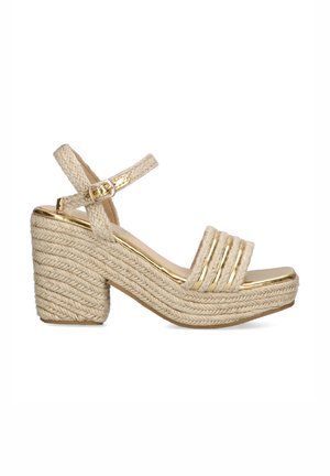Sandalia de plataforma beige con cuña de cuerda trenzada y un acento metálico dorado. Diseño de tiras, hebilla en el tobillo y punta al aire.