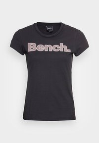 Camiseta de algodón negra con cuello redondo, mangas cortas y el logo "Bench." en blanco con un patrón de puntos en el pecho.