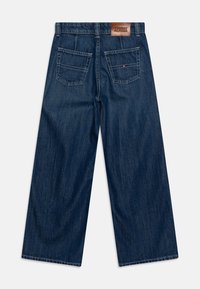 Vaqueros de pierna ancha color azul oscuro hechos de mezclilla. Cuentan con cinco bolsillos, un parche de cuero con la marca en la parte trasera y un diseño de corte recto.