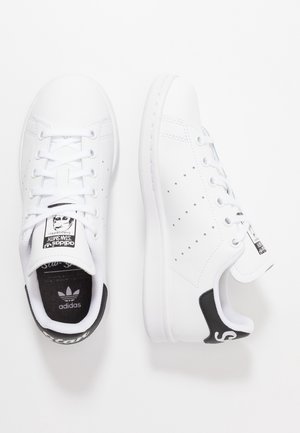 Par af hvide Adidas Stan Smith-sneakers med sorte hælflapper og snøredesign, vist fra top- og sidevisning på hvid baggrund.