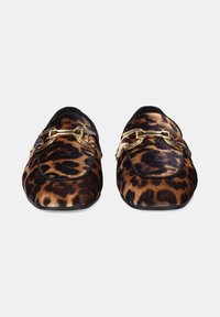 Un par de mocasines de estampado de leopardo con detalle de estribo dorado y ribete negro, exhibidos de frente sobre un fondo blanco.