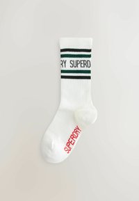 Hvide bomuldsankelsokker med grønne og sorte vandrette striber og "SUPERDRY" tekst; har rød logodetalje nederst.
