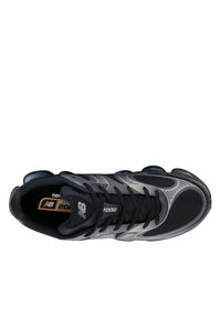 Zapatilla deportiva negra con parte superior de malla, acentos grises, almohadillas de amortiguación redondas y un diseño con cordones que incluye una puntera reforzada.