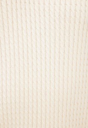 Flødefarvet stof med en kabelstrikket mønster bestående af lodrette rækker af fletteagtige snoede detaljer og teksturerede masker.