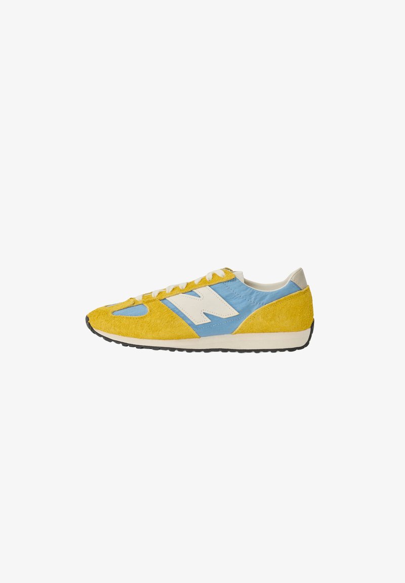 Κίτρινο και μπλε χαμηλό sneaker με λευκά κορδόνια, λευκό λογότυπο στο πλάι και μαύρη λαστιχένια σόλα σε λευκό φόντο.