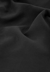 Zwarte stof met een gladde textuur, met zachte plooien en rimpels, zonder duidelijke patronen of accenten.