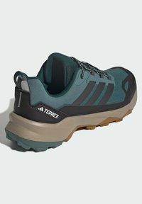 Męskie buty do biegania w terenie Terrex w ciemnozielonym i szarym kolorze, z oddychającą cholewką z siateczki, wytrzymałą podeszwą o dobrym gripie oraz odblaskowymi akcentami.