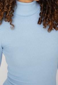 Lichtblauwe geribde turtleneck top, met een getailleerd ontwerp en een gladde textuur. De stof heeft verticale lijnen en een hoge halslijn.