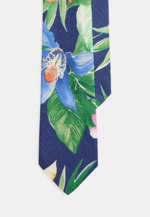 Krawat z niebieskim tłem, na którym znajdują się duże zielone liście oraz żywe tropikalne kwiaty w odcieniach niebieskiego, pomarańczowego, różowego i żółtego.
