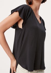 Top corto nero a maniche corte con scollo a V, caratterizzato da maniche a volant e spacchi laterali, realizzato in un tessuto leggero e dalla texture liscia.